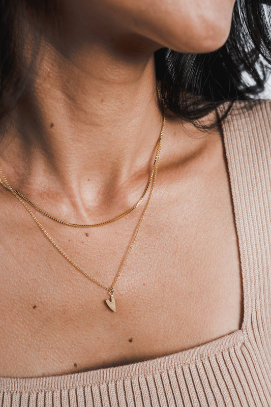 woman wearing gold heart charm necklace