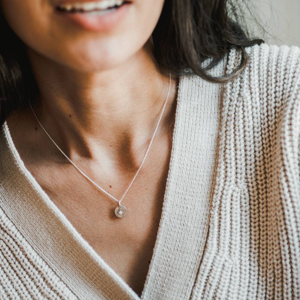 Close-up of a person wearing a delicate necklace by Becoming Jewelry with a small pendant.