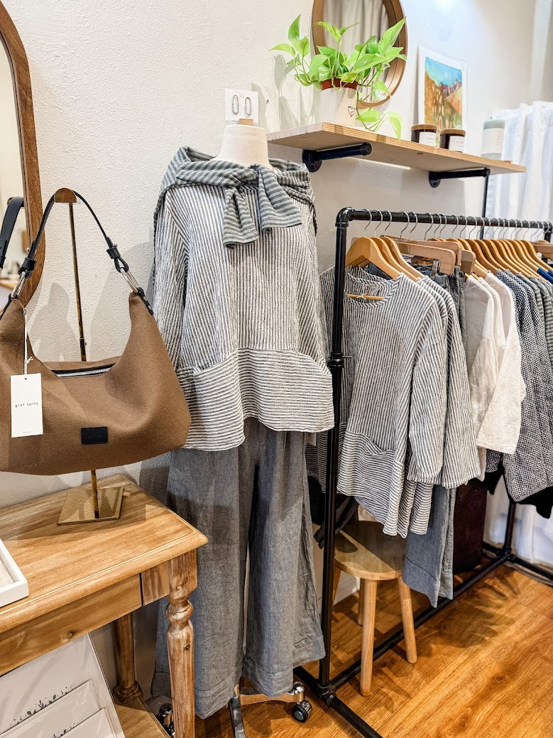 Cut Loose Clothing and accessories displayed at Poppy & Hawk in Camas, WA with a wooden table, mirror, and rack.